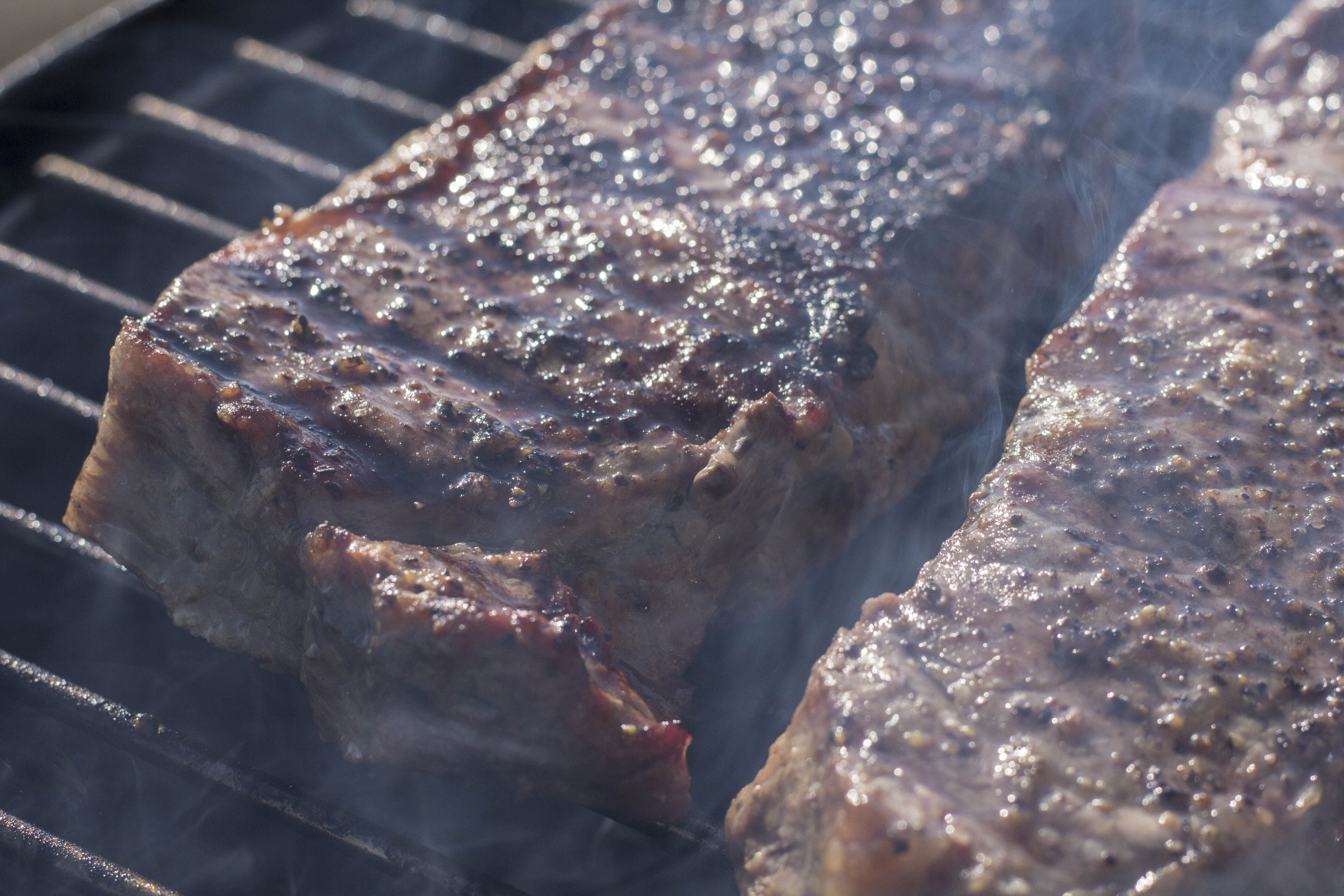 steaks smoking on a grill